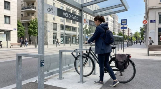 Une personne vue de dos range son vélo dans un abri extérieur moderne équipé de grilles de ventilation, geste naturel en fin de journée